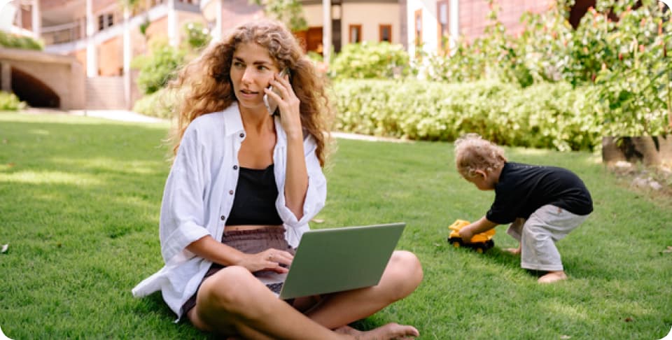 Person having a work call and working on a laptop on grass