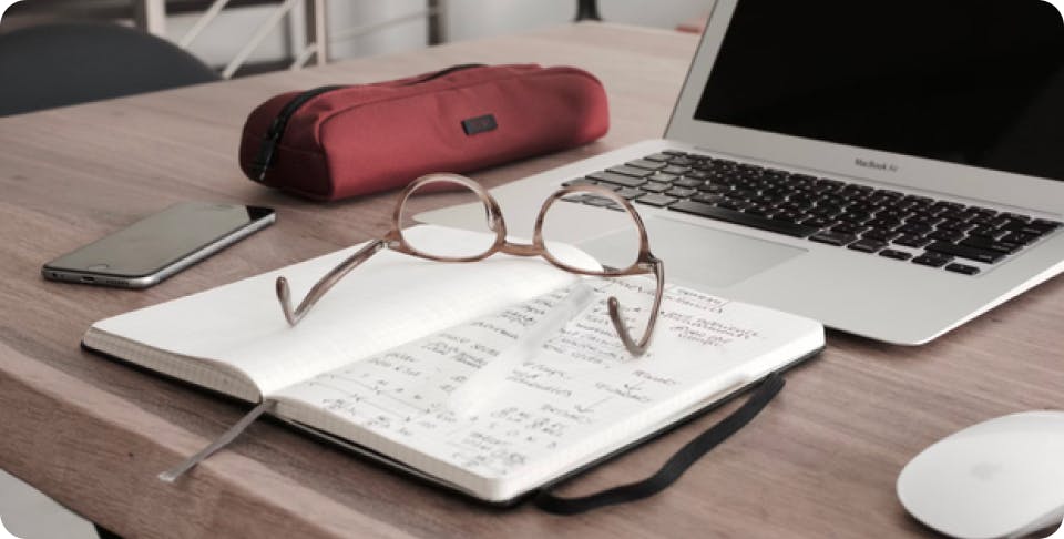 Eyeglasses on top of notes and a laptop